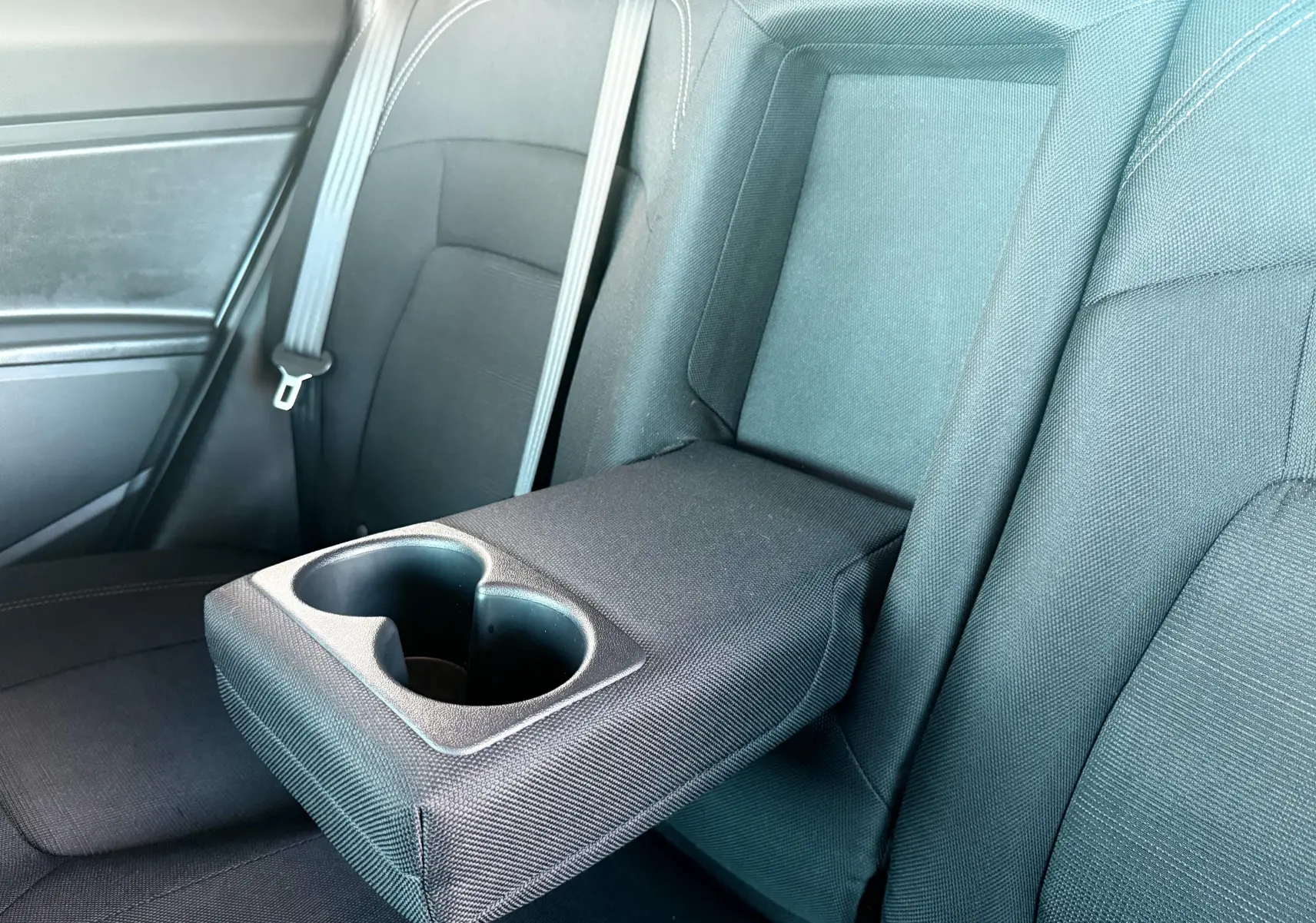 Accoudoir central arrière déployé avec porte-gobelets dans l'habitacle noir du Kia Sportage blanc 2015.