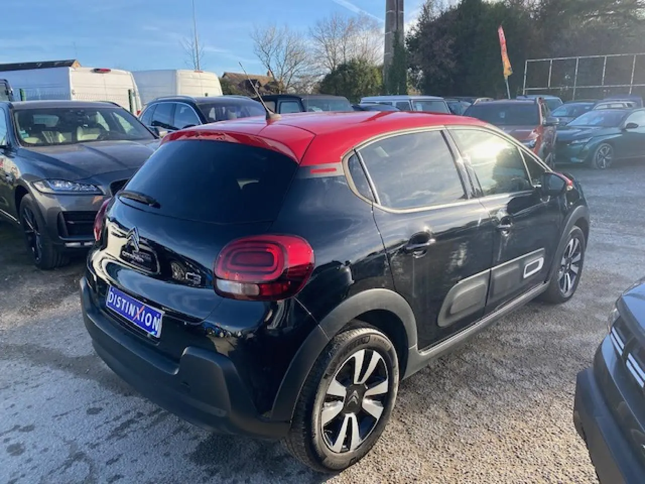 Citroën C3 2023 noir avec toit rouge, vue 3/4 arrière droit, vitres surteintées et protections latérales grises.