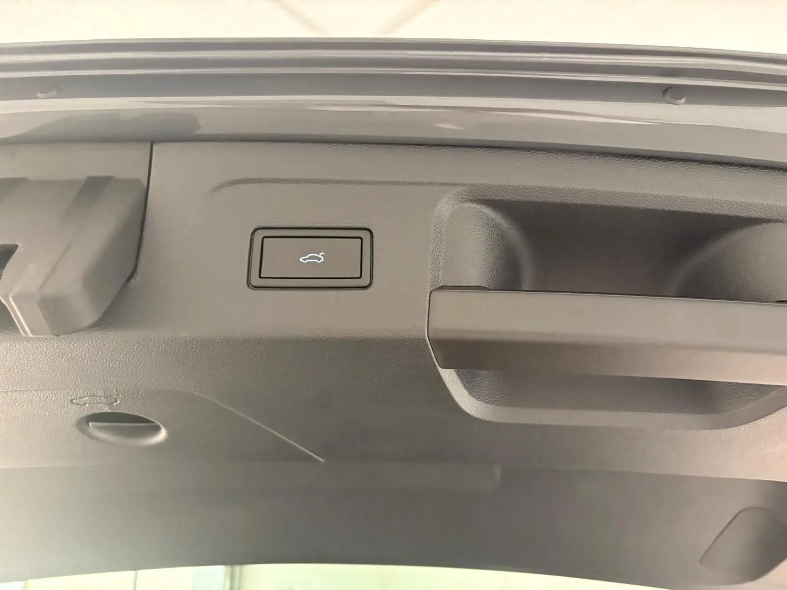 Bouton d'ouverture électrique du hayon sur la partie intérieure du coffre du Volkswagen Touran gris Dauphin 2025.