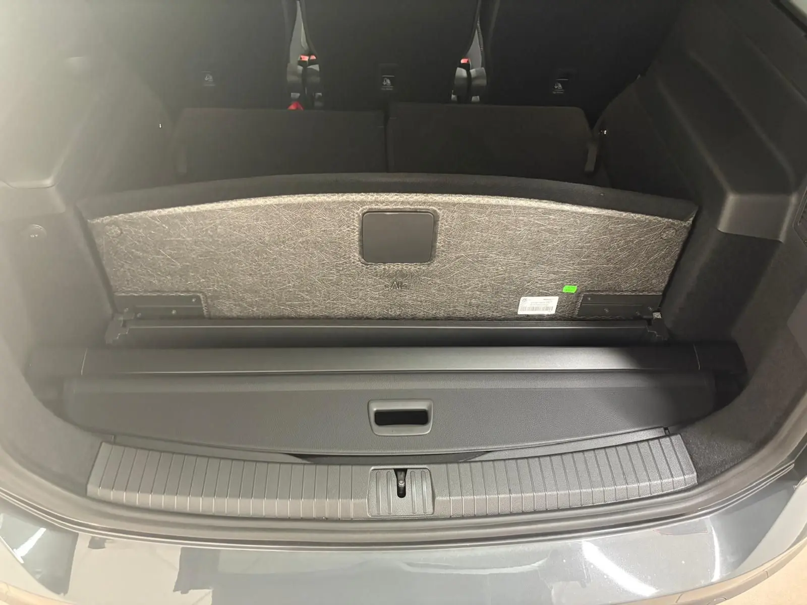 Coffre ouvert du Volkswagen Touran gris dauphin 2025, vue arrière montrant la tablette cache-bagages et banquette rabattue.
