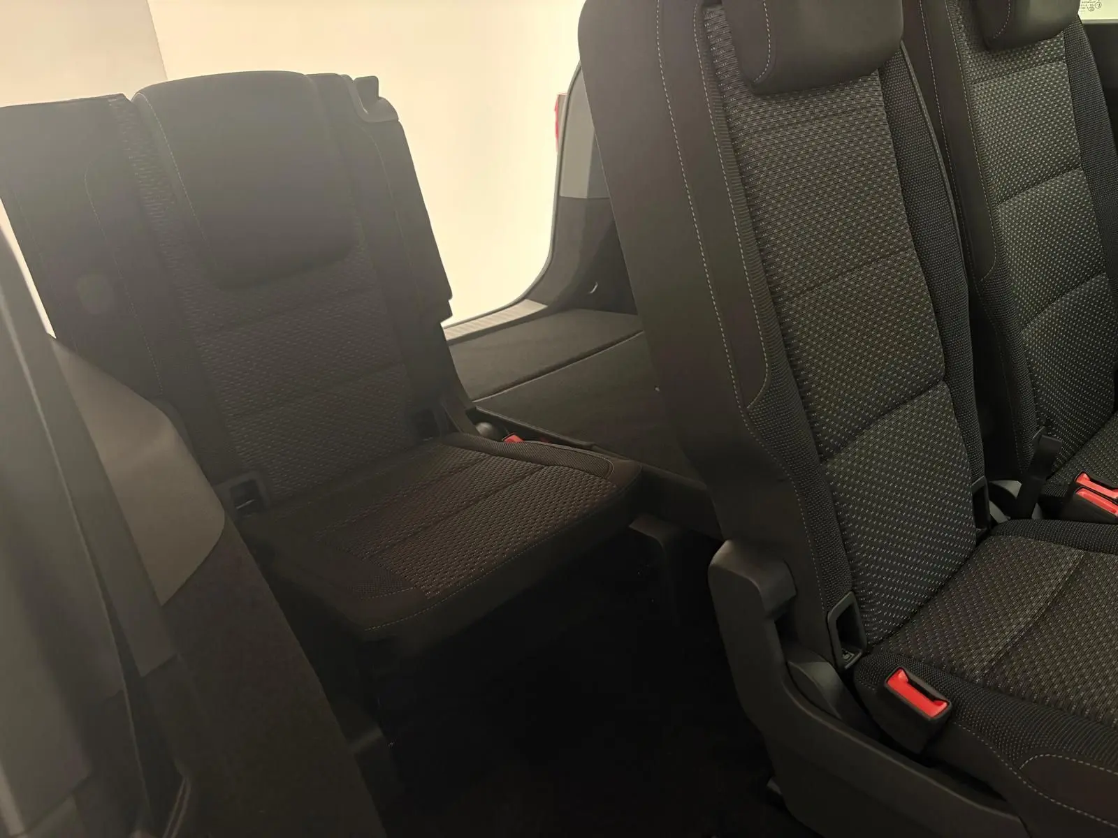 Vue intérieure sur les sièges arrière en tissu noir du Volkswagen Touran 2025, mettant en valeur la troisième rangée rabattable.