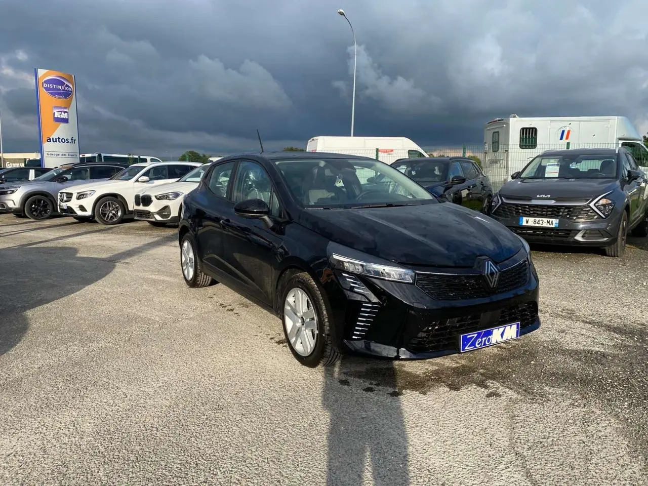 Renault Clio 2025 noir Étoile vue 3/4 avant droit sur parking avec éclairage naturel et ciel nuageux.