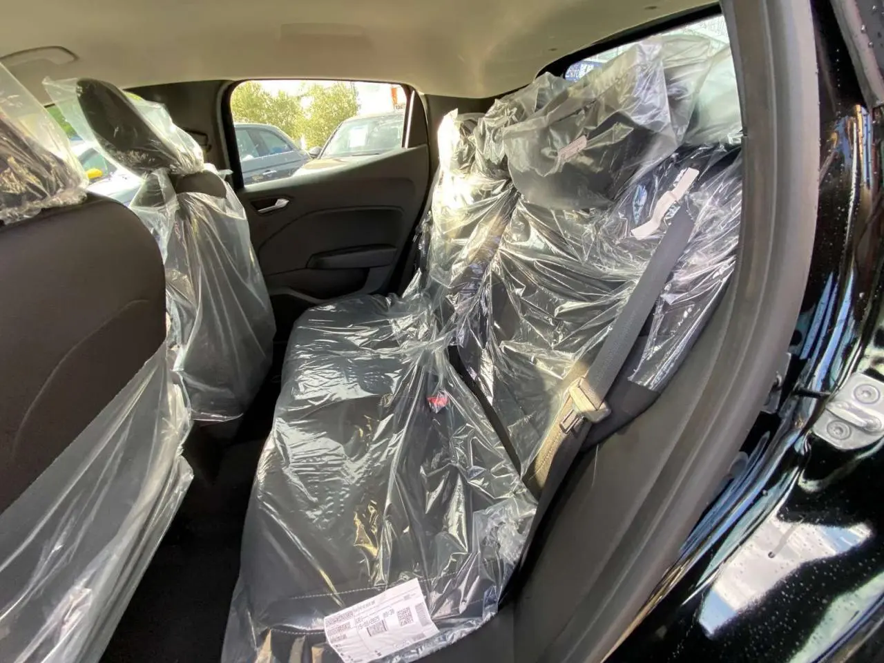 Vue intérieure côté droit des sièges arrière noirs protégés par des housses plastiques dans une Renault Clio 2025.