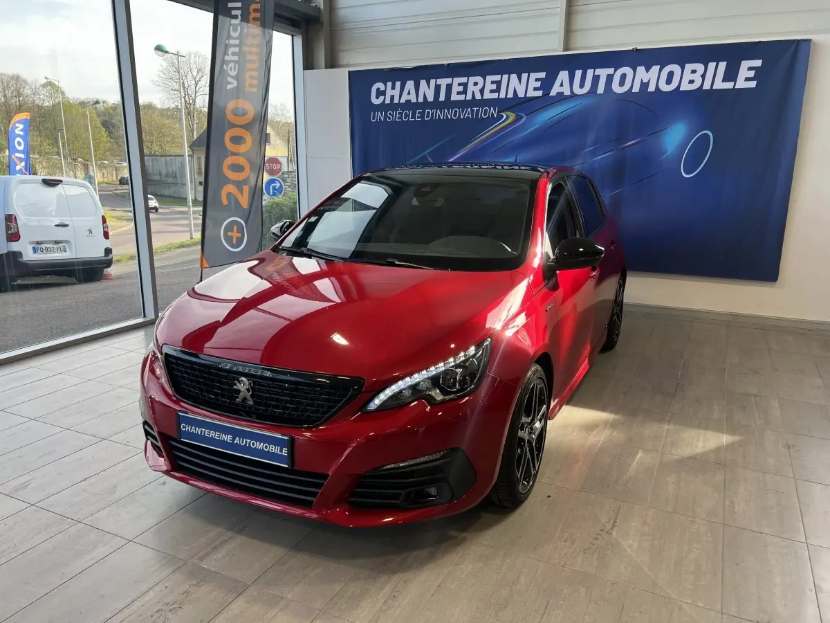 Peugeot 308 Puretech 130 S&S GT Line rouge vue en 3/4 avant droit dans un showroom avec jantes noires.