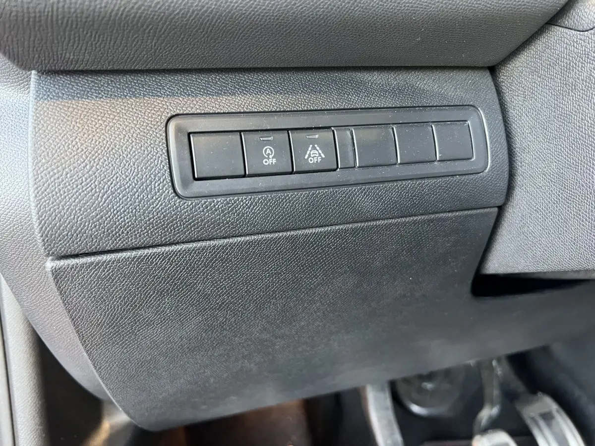 Gros plan sur les boutons de désactivation du système start-stop et de l'aide au maintien de voie dans une Peugeot 308 GT Line rouge de 2019.