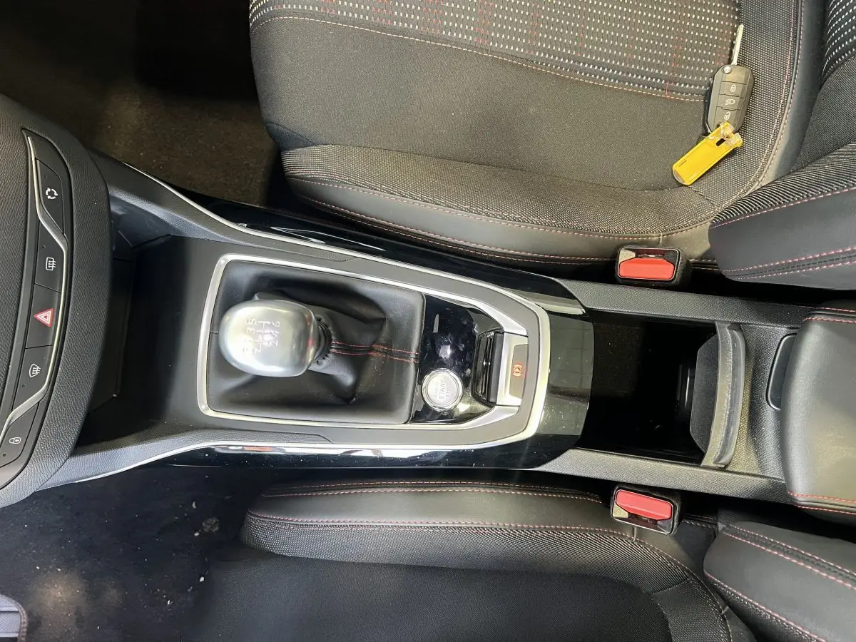 Vue plongeante sur la console centrale et levier de vitesse manuelle d'une Peugeot 308 GT Line rouge, avec clé posée sur siège.
