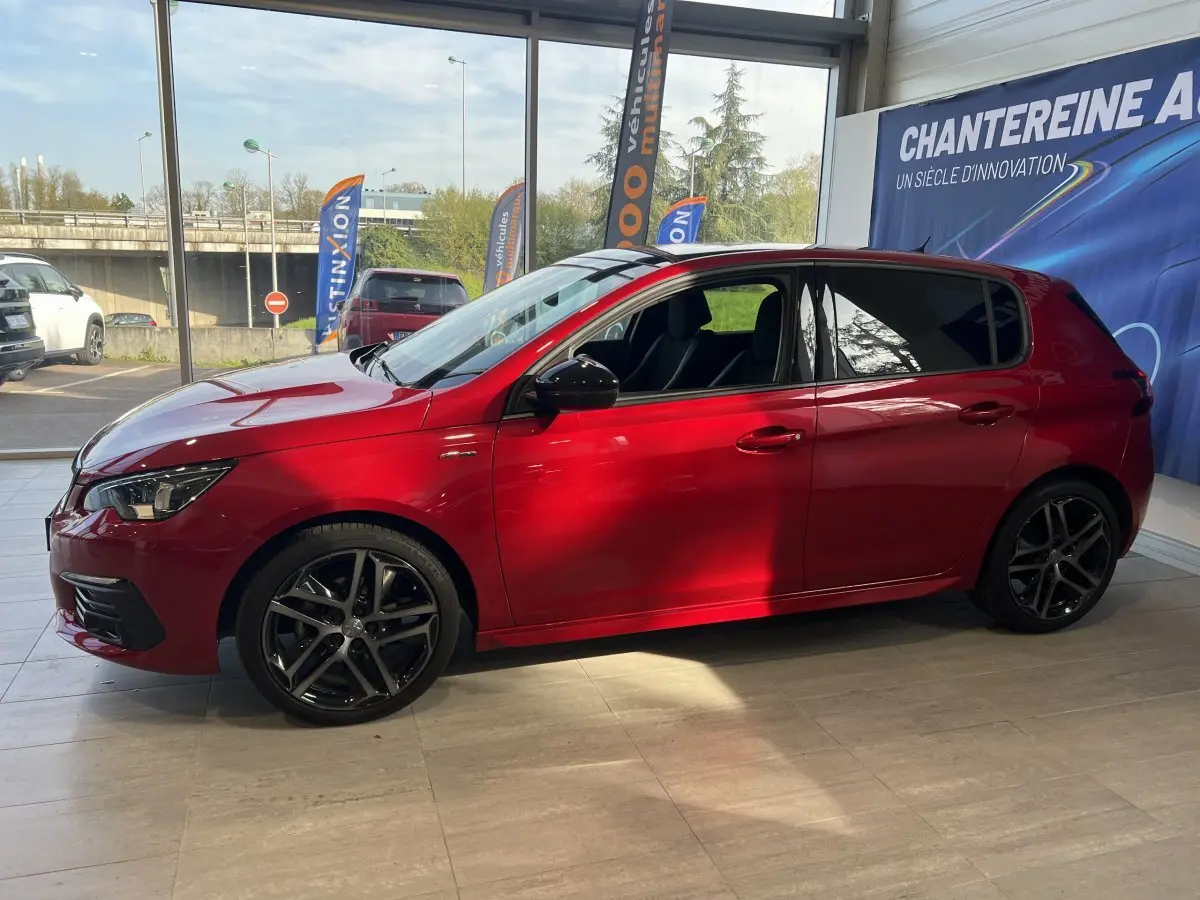 Peugeot 308 Puretech 130 S&S GT Line rouge vue de profil côté gauche en intérieur avec jantes alliage noires.