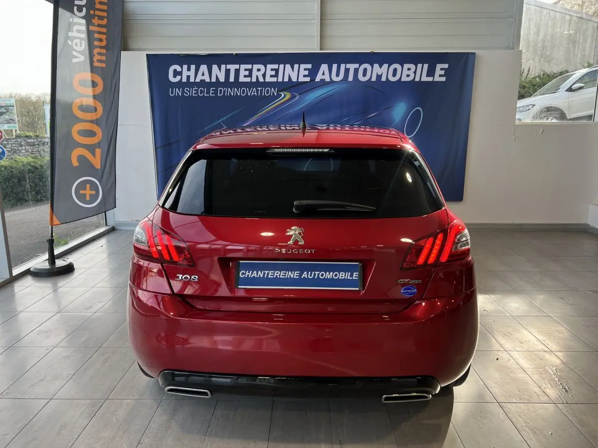 Vue arrière d'une Peugeot 308 Puretech 130 S&S GT Line rouge, avec feux LED et double sortie d'échappement chromée.