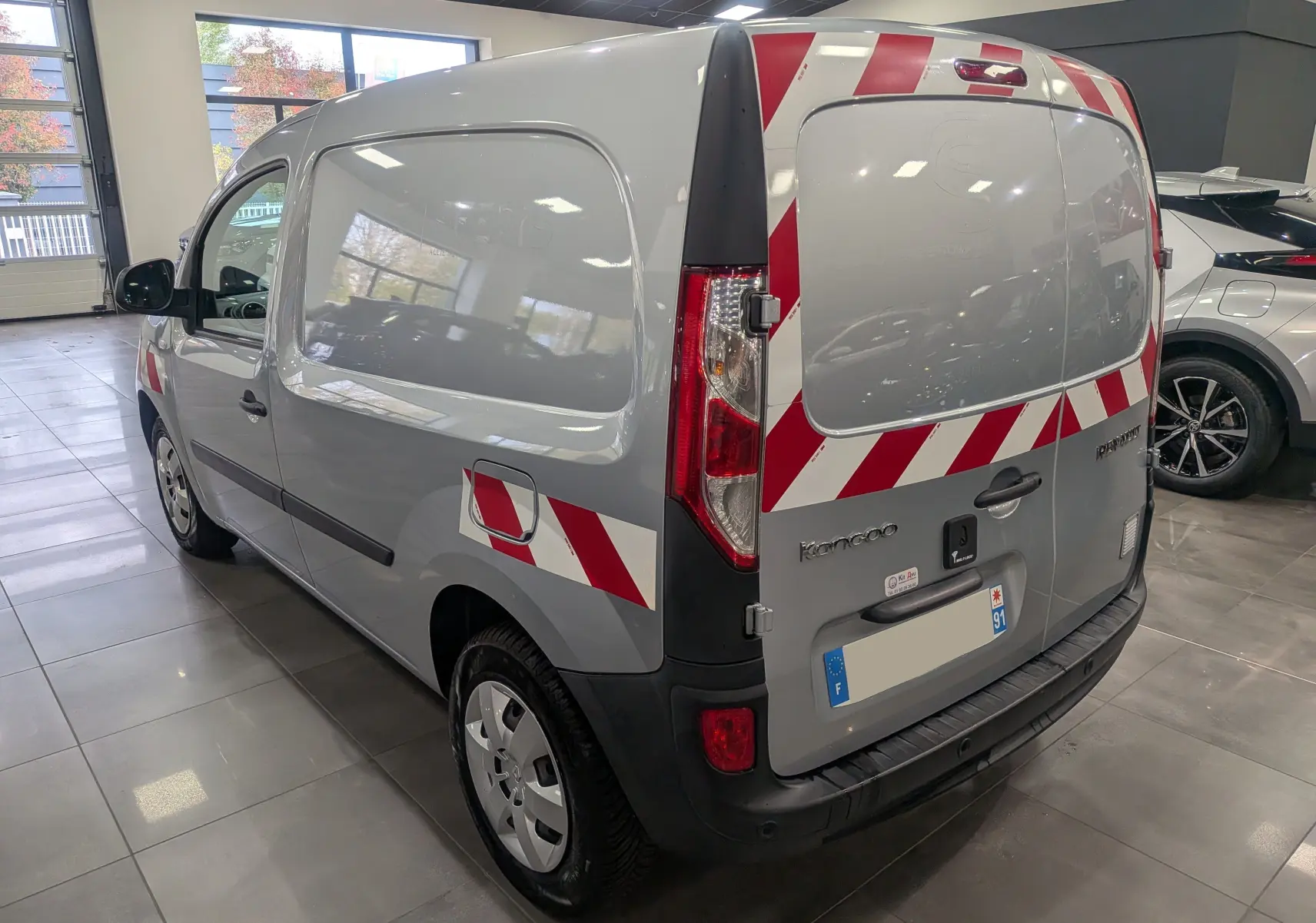 Renault Kangoo Express gris Highland vu en 3/4 arrière droit avec bandes rouges et blanches de sécurité.