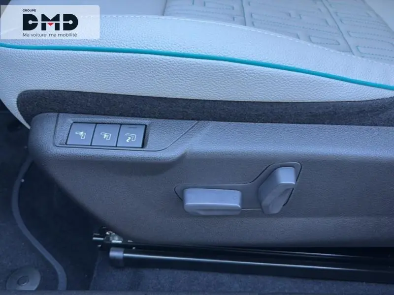 Détail des commandes de réglage électrique du siège conducteur gris clair avec surpiqûres bleues sur une FIAT 600 rouge.