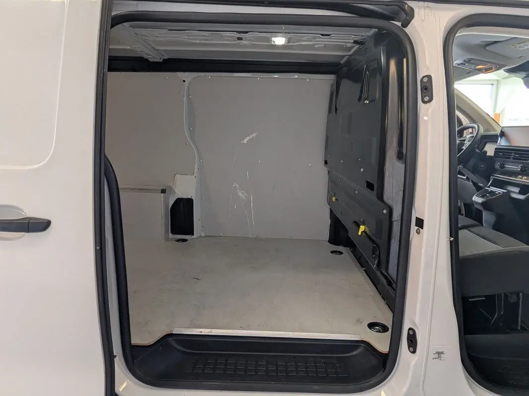 Vue intérieure du fourgon FIAT Scudo XL blanc 2025, montrant l'espace de chargement vide et la cabine côté droit.