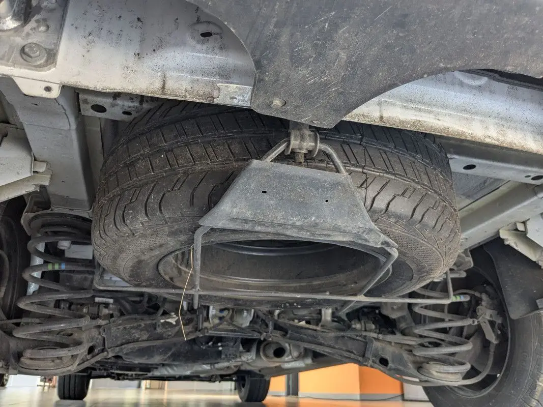 Vue en contre-plongée sous le FIAT Scudo Fourgon blanc, montrant la roue de secours suspendue et la suspension arrière.
