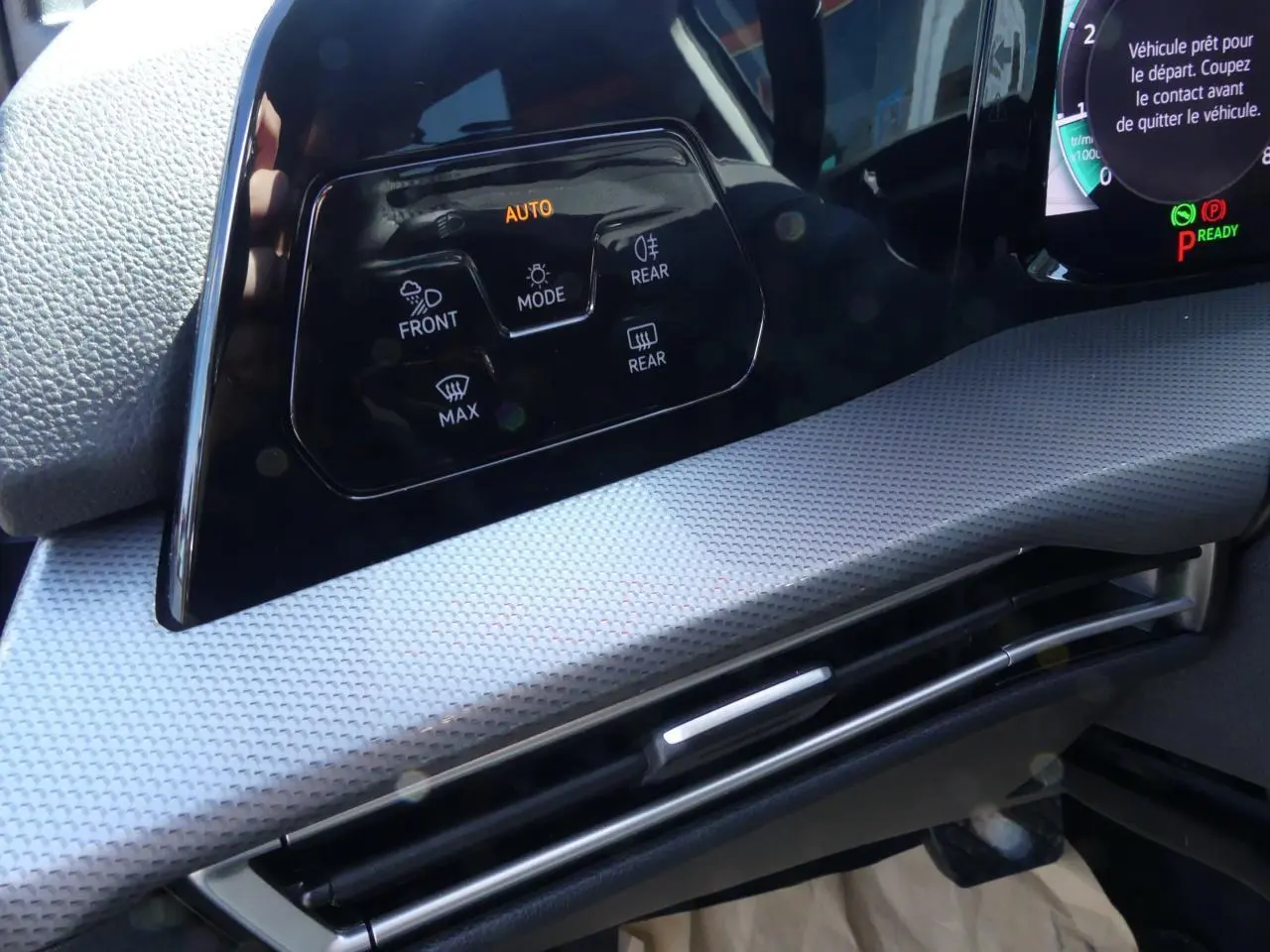 Détail du tableau de bord gris clair de la Volkswagen Golf 2024 avec commandes d’éclairage et ventilation intégrées.