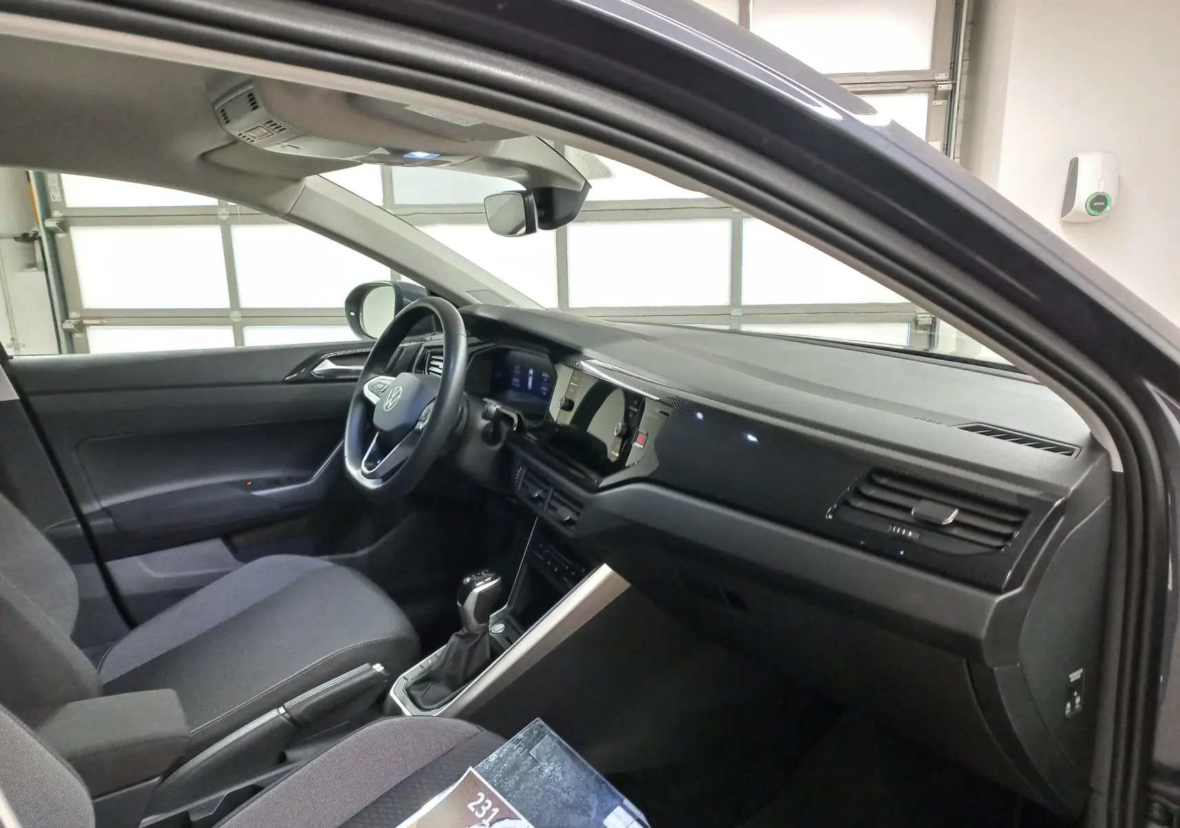 Vue intérieure côté conducteur du Volkswagen Taigo 2025, tableau de bord noir avec volant multifonction et console centrale moderne.