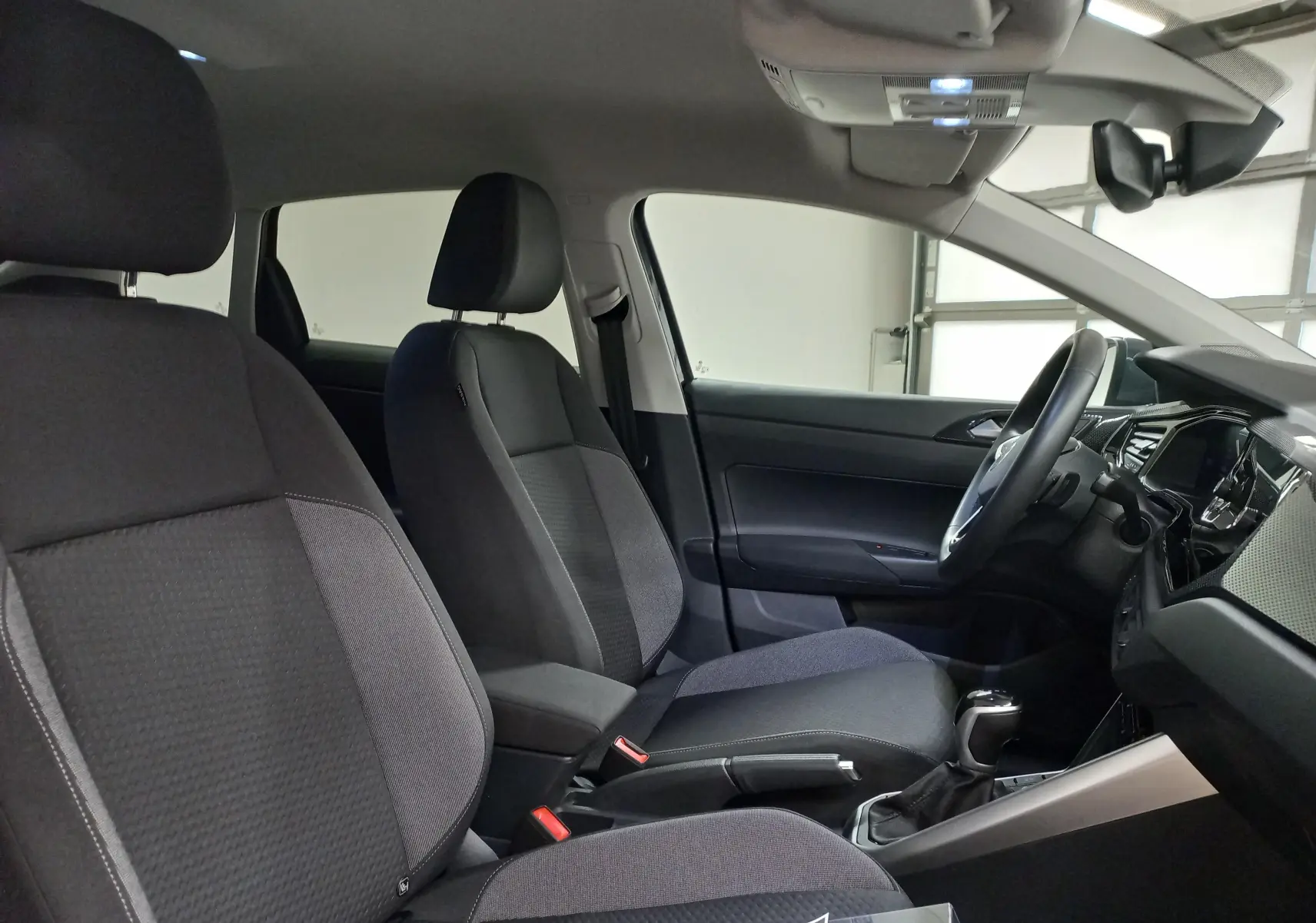 Vue intérieure côté conducteur du Volkswagen Taigo 2025, sièges tissu gris et tableau de bord moderne.