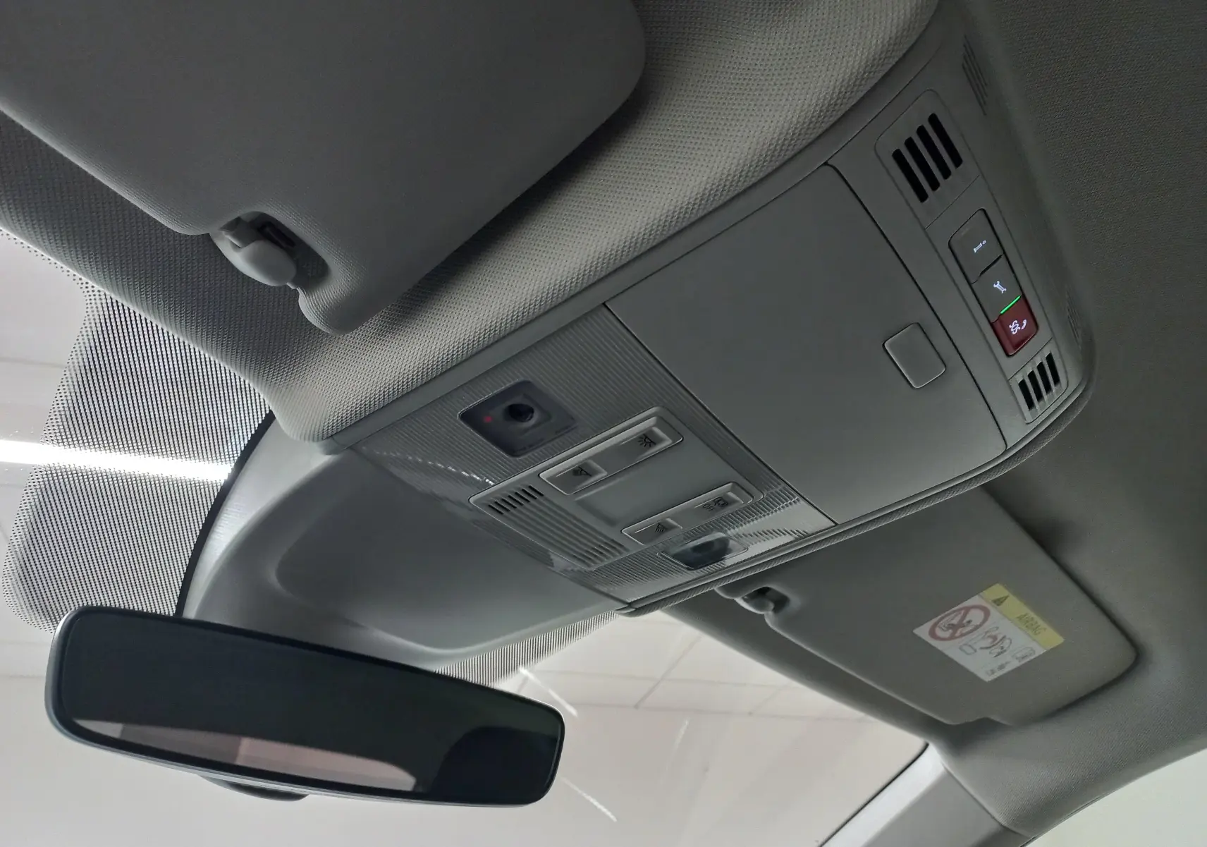 Vue intérieure du plafond avant du Volkswagen Taigo gris cendre, avec commandes d'éclairage et rétroviseur central.