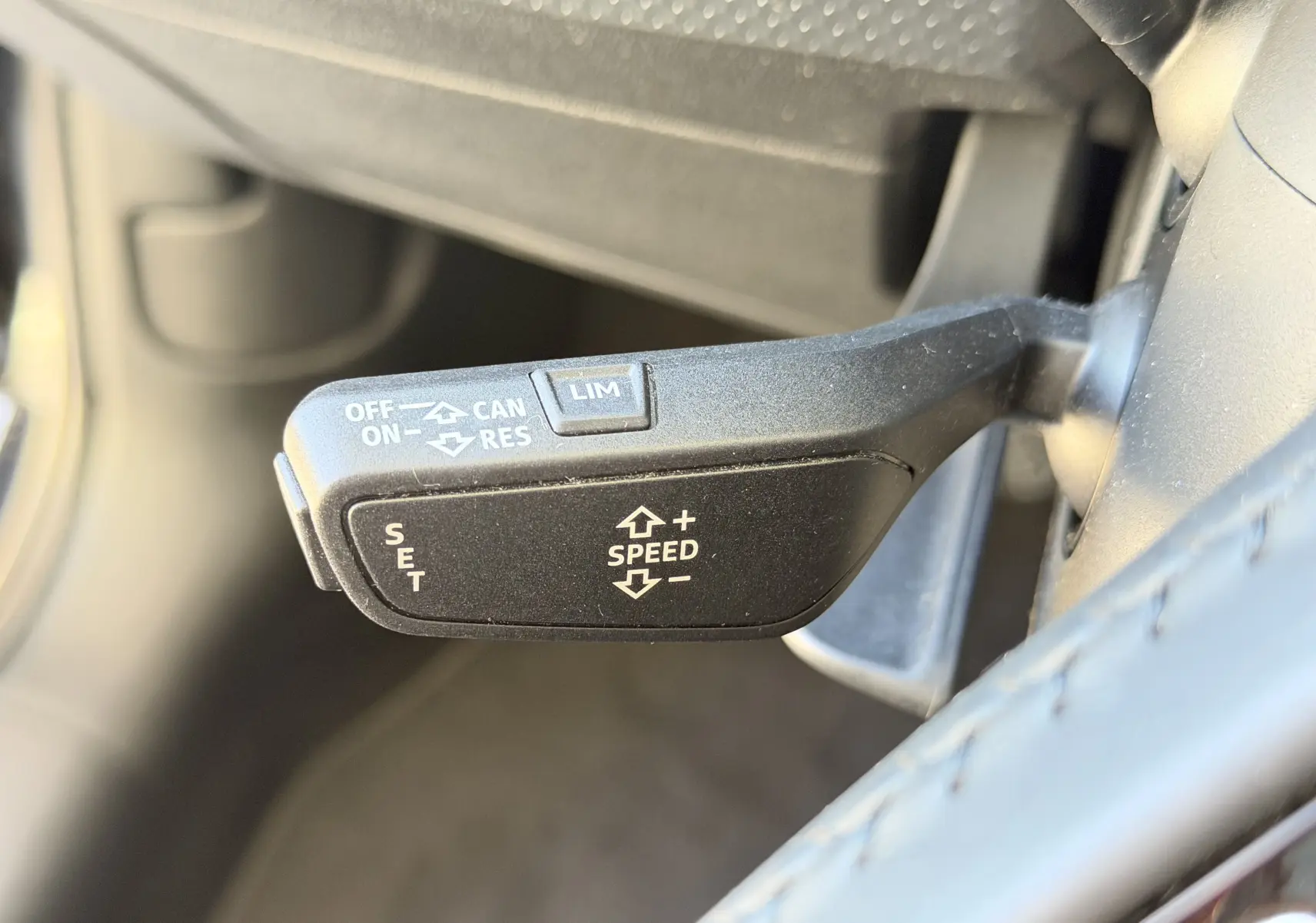 Le levier de régulateur de vitesse noir vu en gros plan côté gauche du volant dans l’habitacle d’une Audi A1 Sportback 2020 bleu firmament.