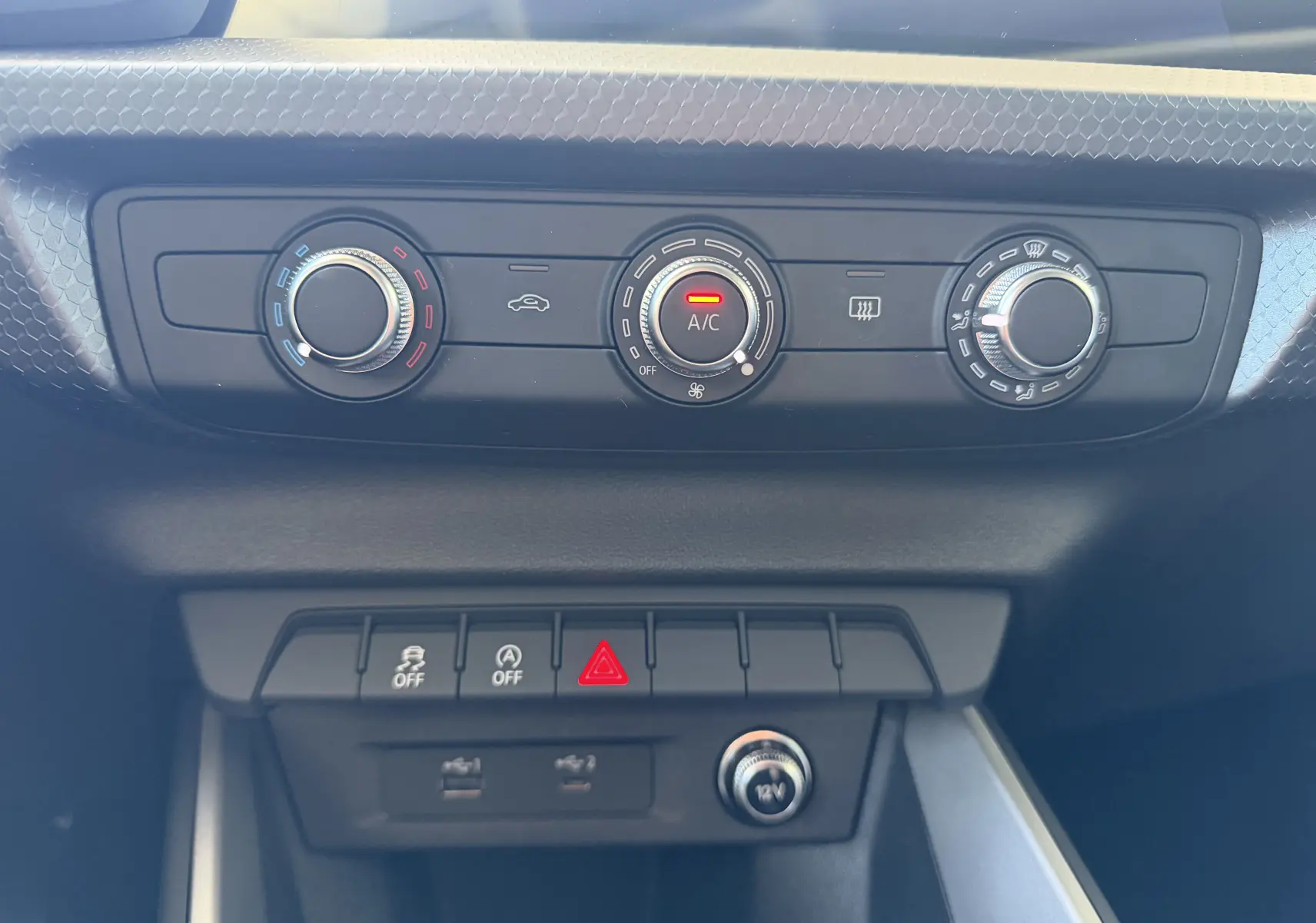 Vue rapprochée de la console centrale de l'Audi A1 Sportback 2020, montrant les commandes de climatisation et boutons de sécurité.