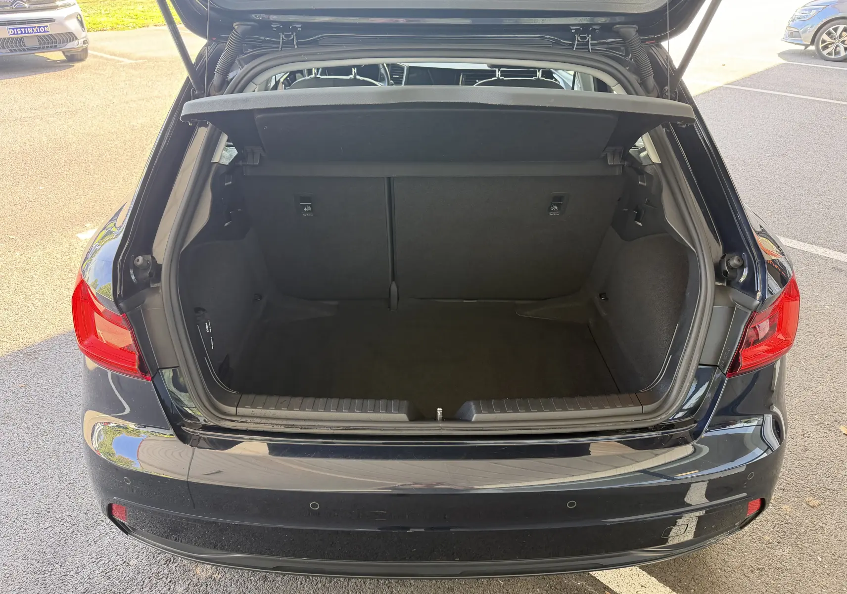 Coffre ouvert vu de l'arrière d'une Audi A1 Sportback bleu firmament, montrant l'espace de chargement vide et la tablette cache-bagages.