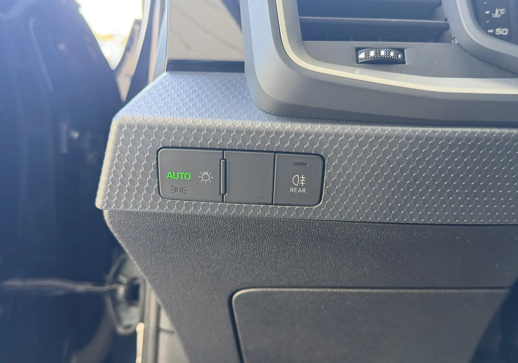 Détail du tableau de bord côté gauche de l'Audi A1 Sportback 2020 bleu firmament, avec commandes d'éclairage automatique et antibrouillard arrière.