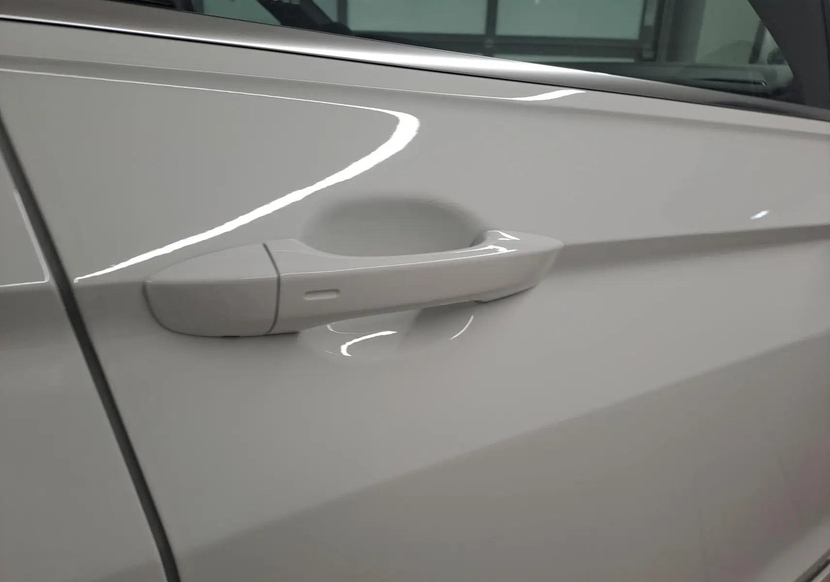 Poignée de porte blanche côté gauche du Volkswagen Tiguan 1.4 eHybrid 245 DSG6 R-LINE 2023 en gros plan.