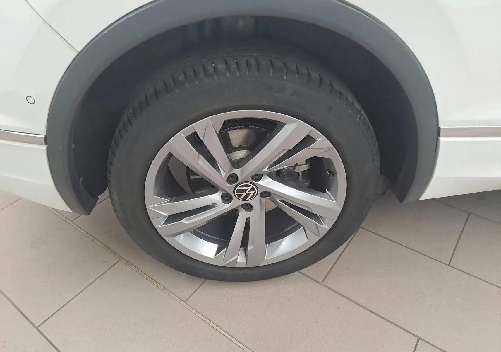 Gros plan sur la roue avant gauche du Volkswagen Tiguan blanc pur 2023 avec jante alliage R-Line distinctive.