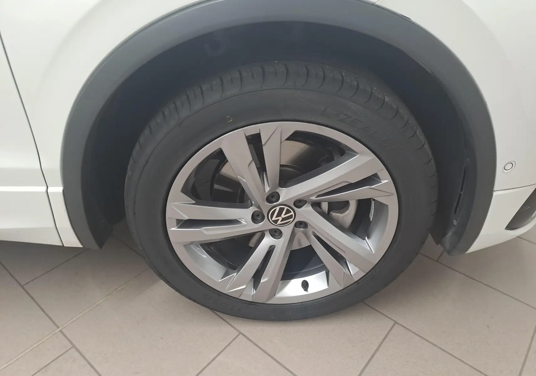 Gros plan sur la roue avant gauche du Volkswagen Tiguan blanc pur 1.4 eHybrid 245 DSG6 R-LINE avec jante alliage distinctive.