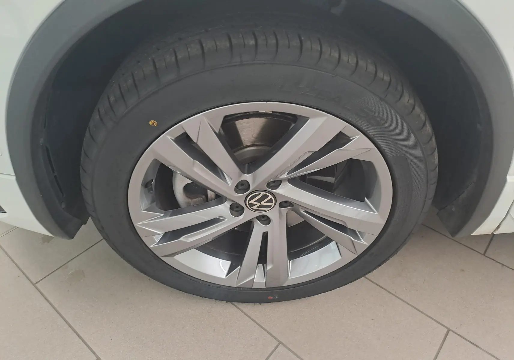 Gros plan sur la roue avant gauche du Volkswagen Tiguan blanc pur 1.4 eHybrid 245 DSG6 R-LINE avec jante alliage distinctive.