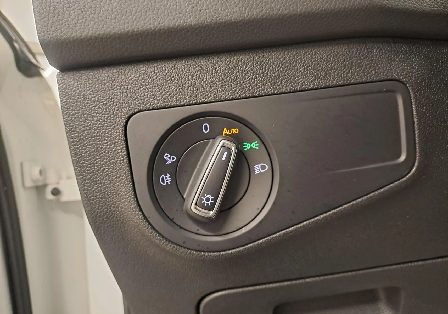 Gros plan sur le bouton de commande des phares dans l’habitacle du Volkswagen Tiguan blanc pur 2023 R-Line hybride rechargeable.