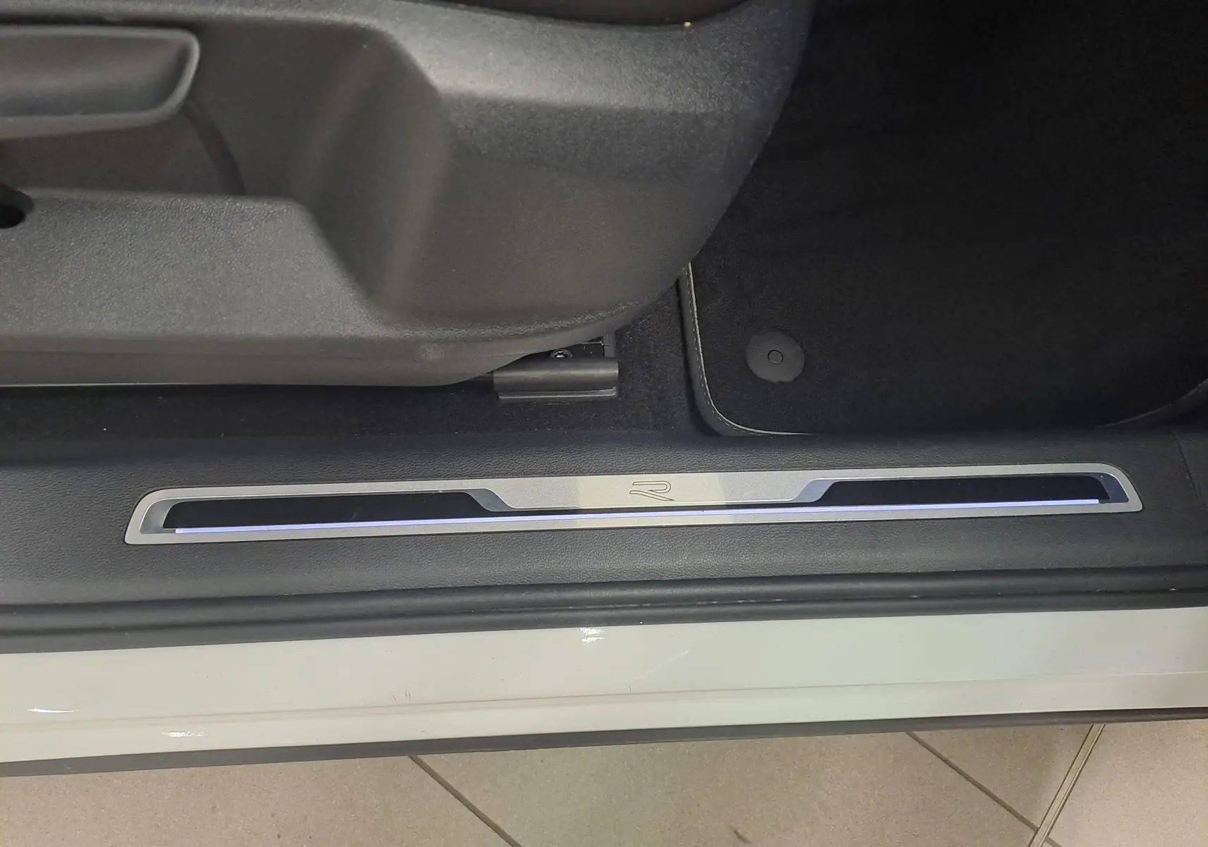 Seuil de porte côté conducteur du Volkswagen Tiguan blanc pur 2023, version R-Line avec éclairage bleu subtil.