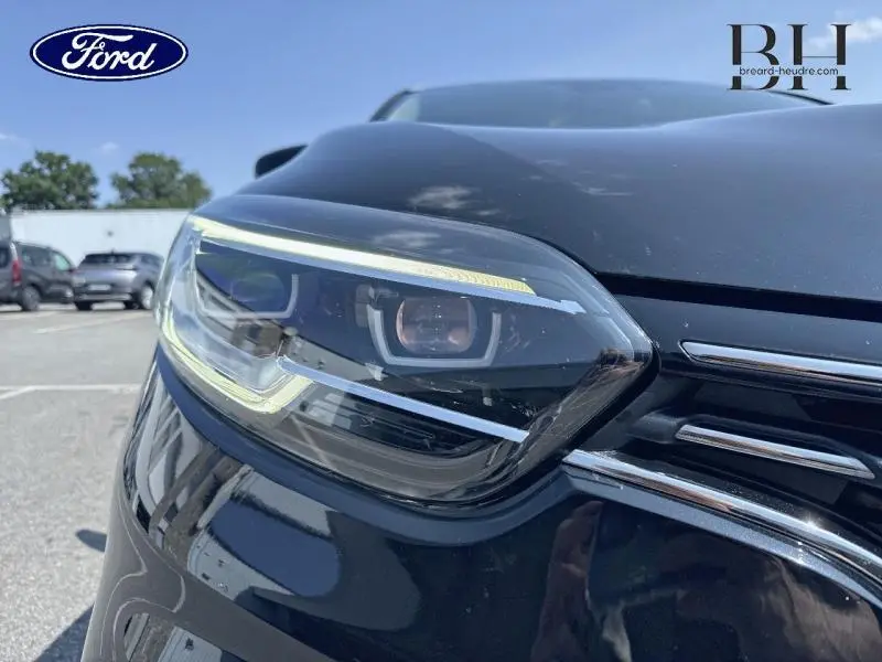 Gros plan sur le phare avant gauche du Renault Kadjar noir étoilé avec calandre chromée visible en extérieur.