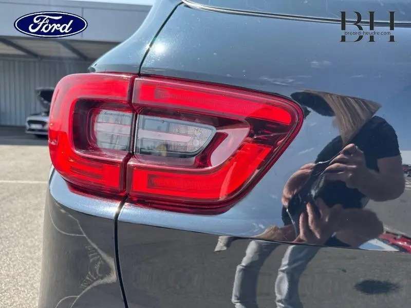 Gros plan sur le feu arrière droit rouge du Renault Kadjar noir étoilé, avec reflet du photographe sur la carrosserie.