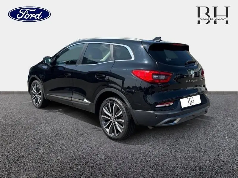 Renault Kadjar noir étoilé vu en 3/4 arrière droit, avec toit en verre fixe et jantes alu distinctives.