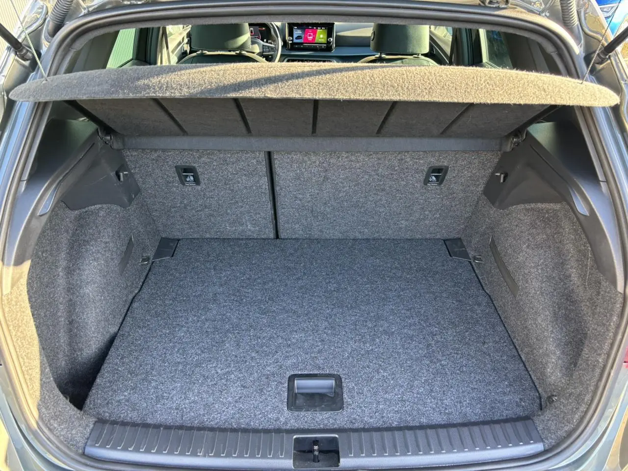 Coffre ouvert vu de l'arrière d'un SEAT Arona gris Cliff, montrant le plancher à double fond et la plage arrière.