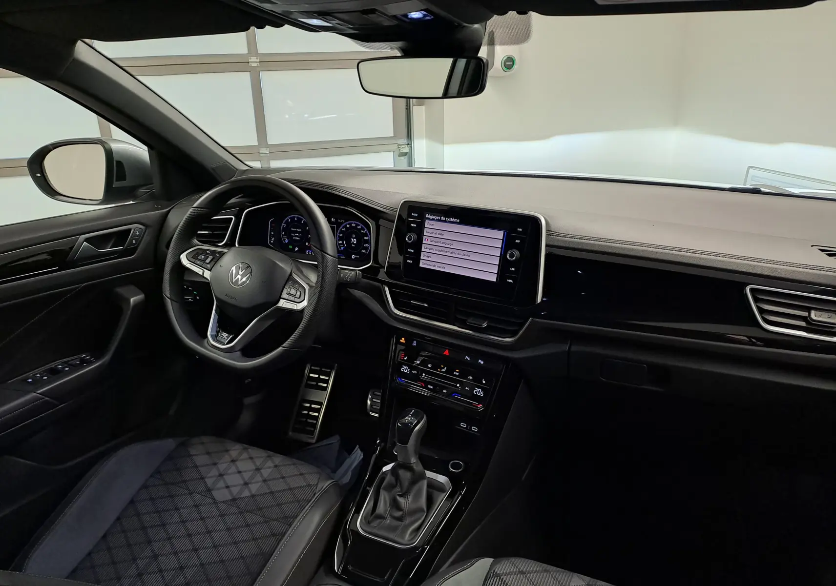 Vue intérieure côté conducteur du Volkswagen T-Roc 1.5 TSI 2025, tableau de bord moderne avec écran tactile central.