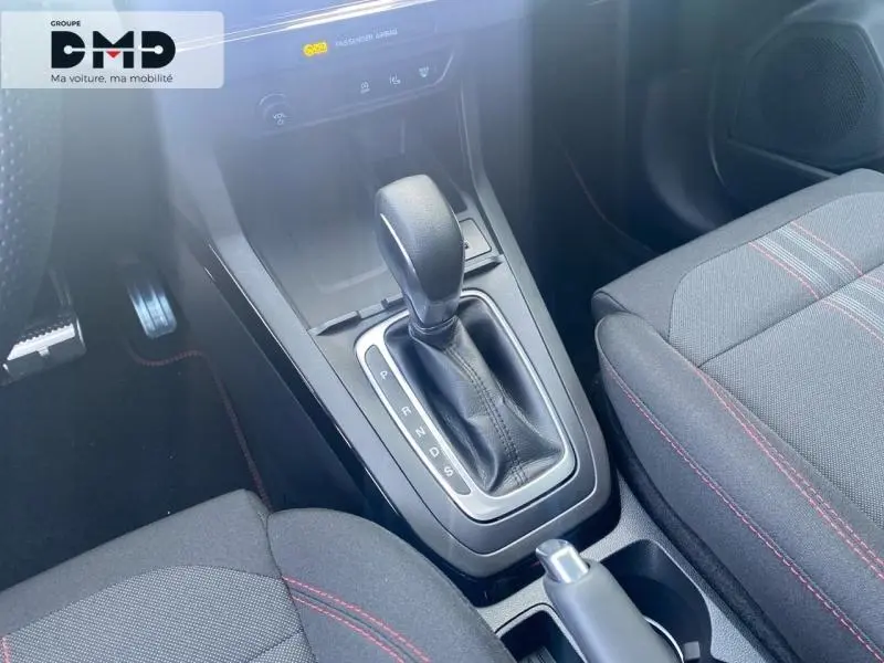 Gros plan sur la console centrale avec levier de boîte auto et sièges sport noirs à surpiqûres rouges dans un Ford Puma 2026.