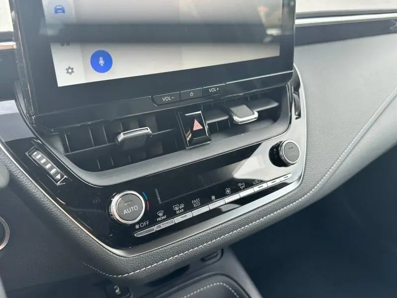 Vue rapprochée de la console centrale noire de la Toyota Corolla 2025 avec écran tactile et commandes climatisation automatiques.