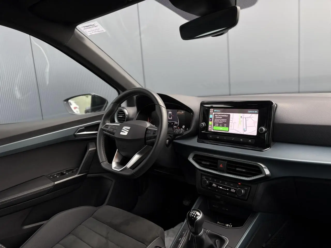 Vue intérieure côté conducteur du tableau de bord du SEAT Arona TSI 115 Xpérience avec écran tactile et volant cuir noir.