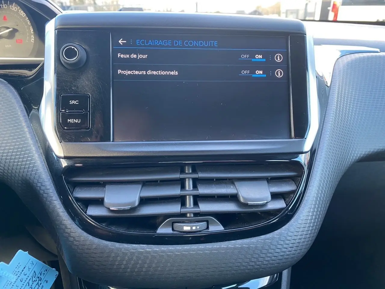 Vue rapprochée de l’écran tactile central du Peugeot 2008 gris platinium de 2019, affichant les réglages d’éclairage de conduite.