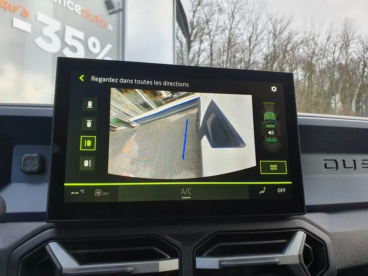 Écran central du Dacia Duster blanc glacier montrant la caméra de recul avec affichage multivues intérieur.