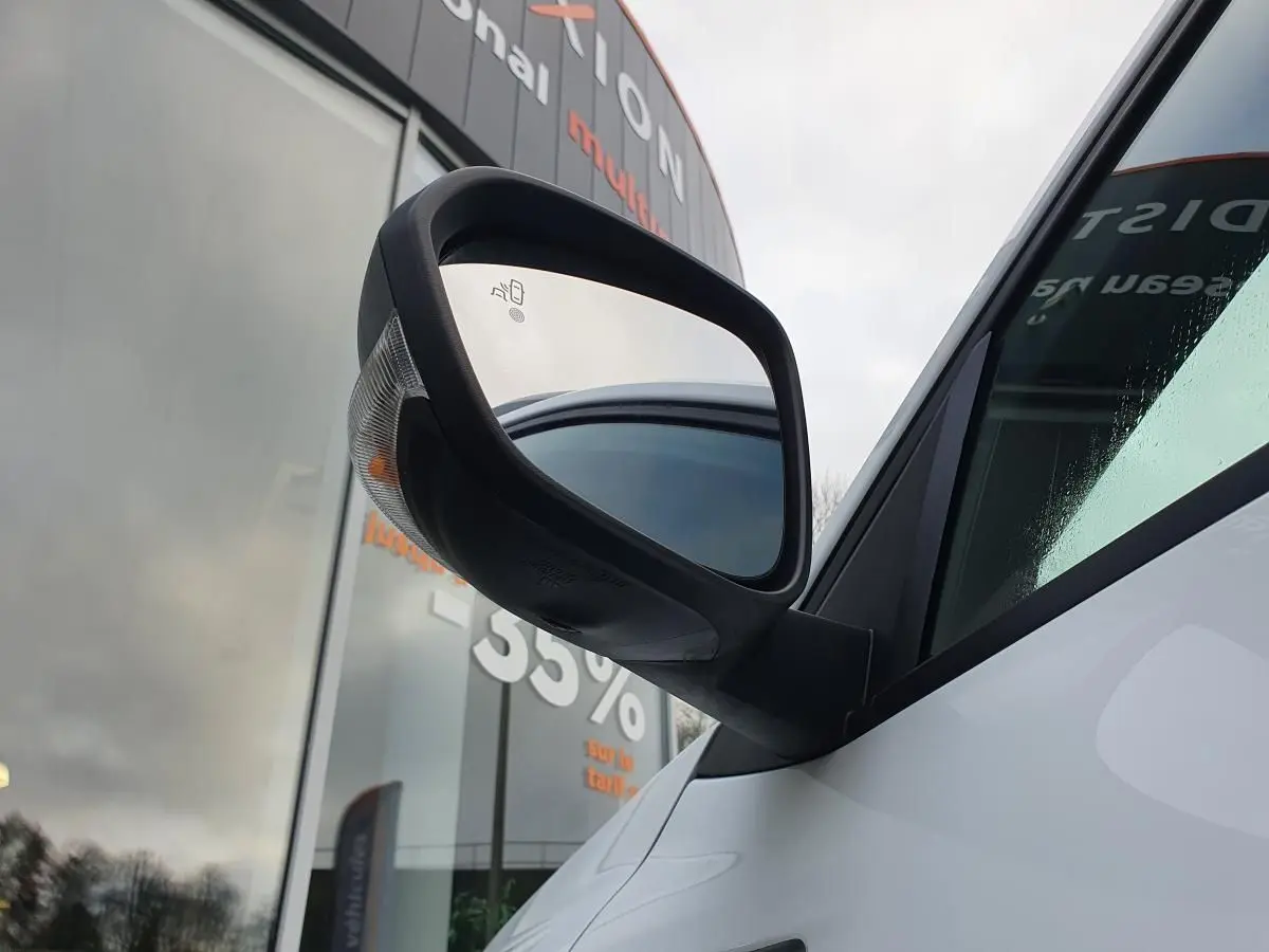 Gros plan sur le rétroviseur droit noir du Dacia Duster blanc glacier, avec vitre teintée en arrière-plan.