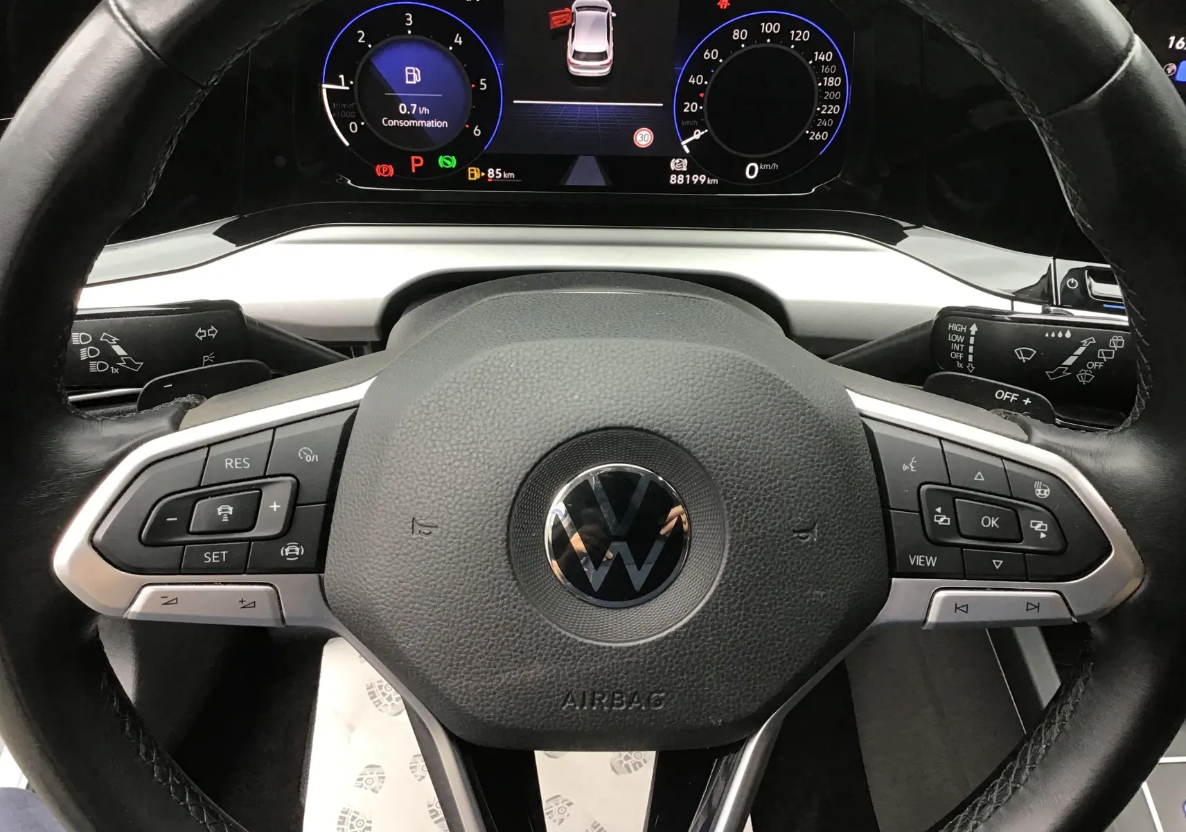 Vue rapprochée du volant noir et du tableau de bord numérique de la Volkswagen Golf VIII gris reflex, affichant le digital cockpit pro.