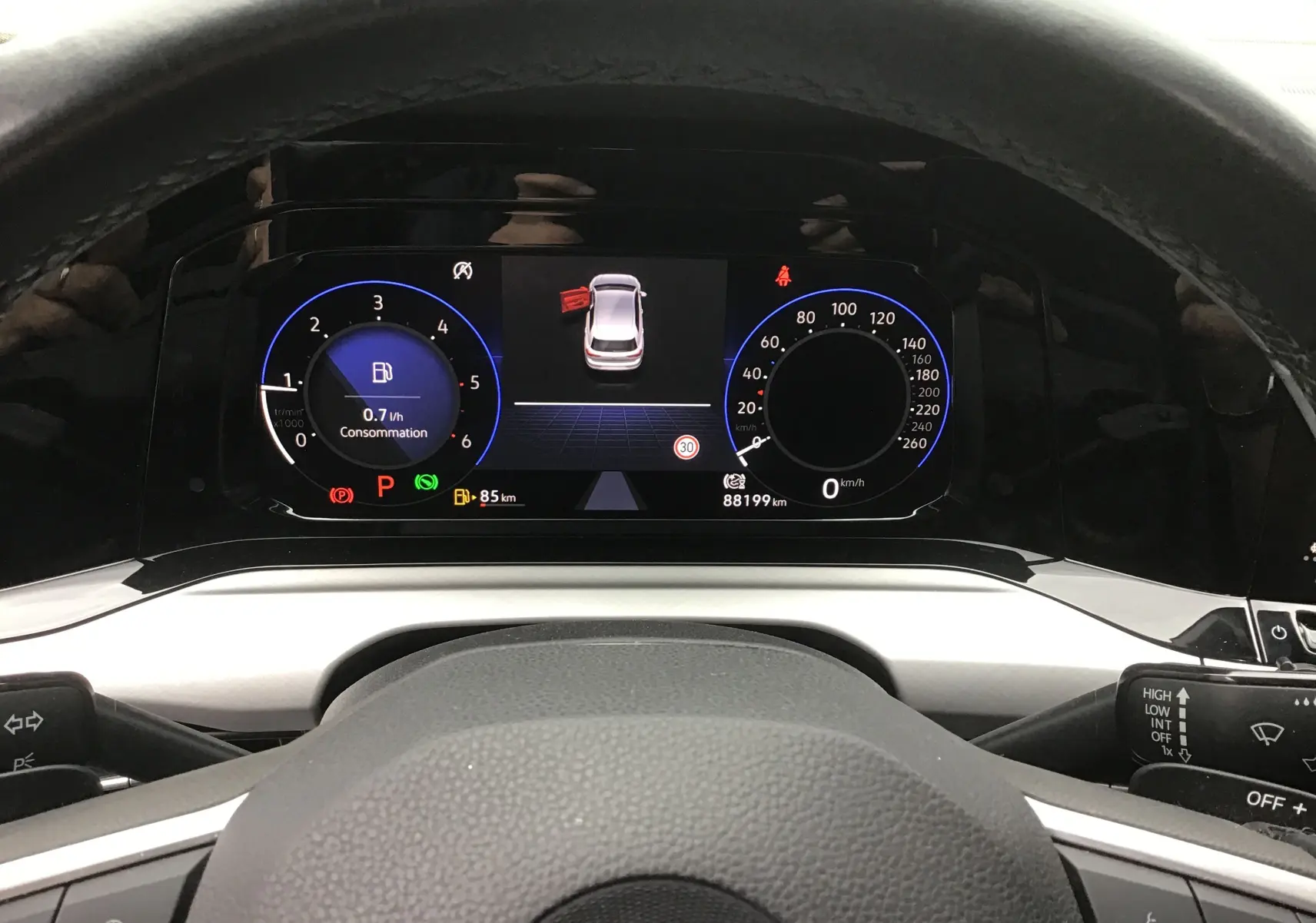 Vue rapprochée du tableau de bord digital pro de la Volkswagen Golf VIII avec affichage consommation et vitesse, volant en cuir noir.