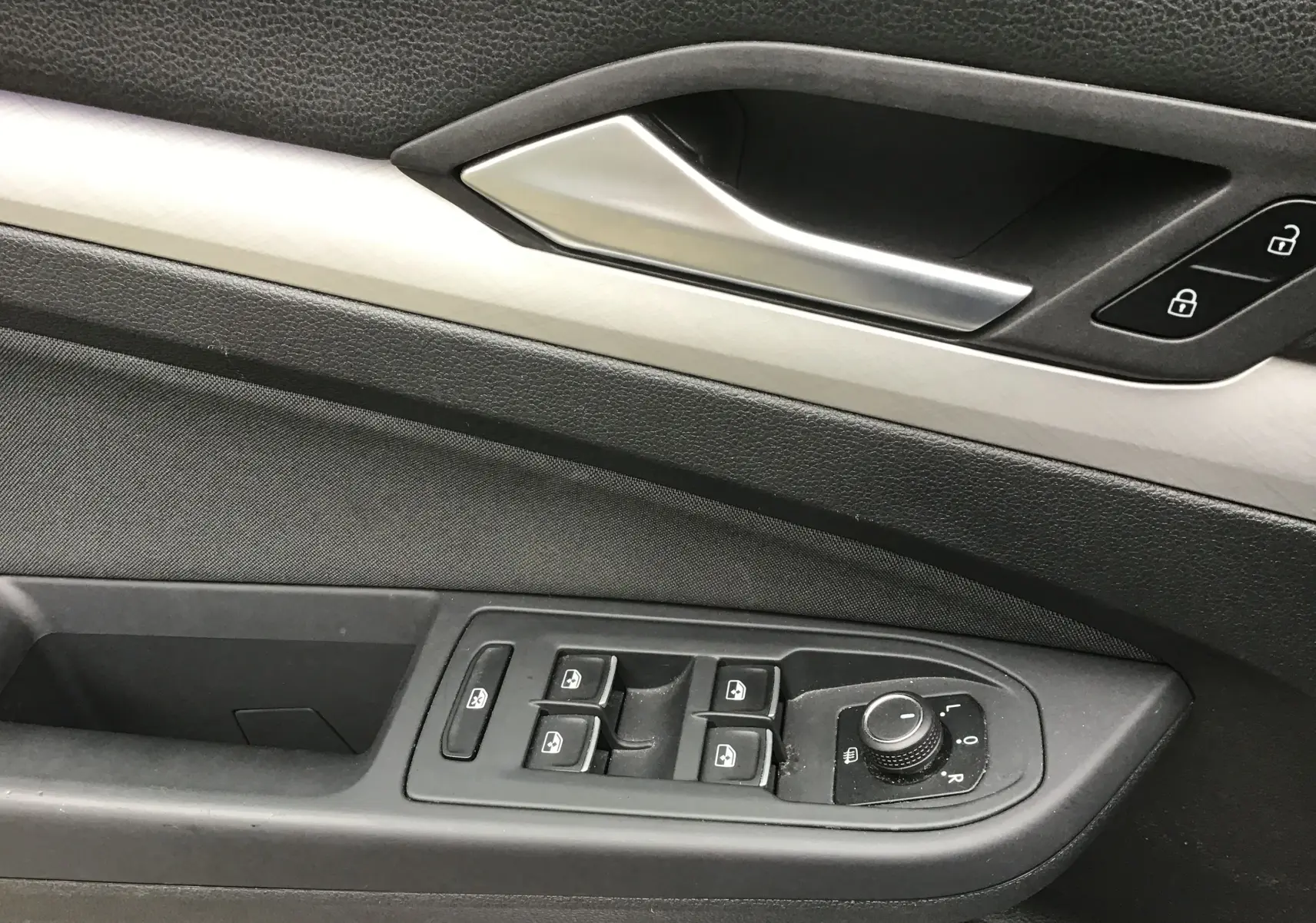 Gros plan sur la commande des vitres et rétroviseurs côté gauche de la porte intérieure d’une Volkswagen Golf VIII gris reflex.