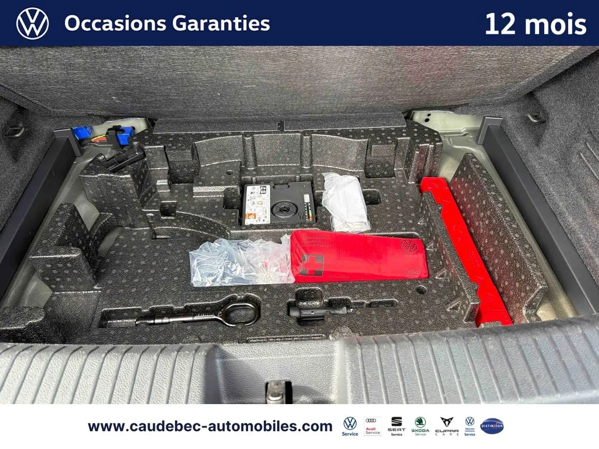 Coffre ouvert du Volkswagen T-Roc Cabriolet noir, montrant le rangement avec kit de secours et outils intégrés.