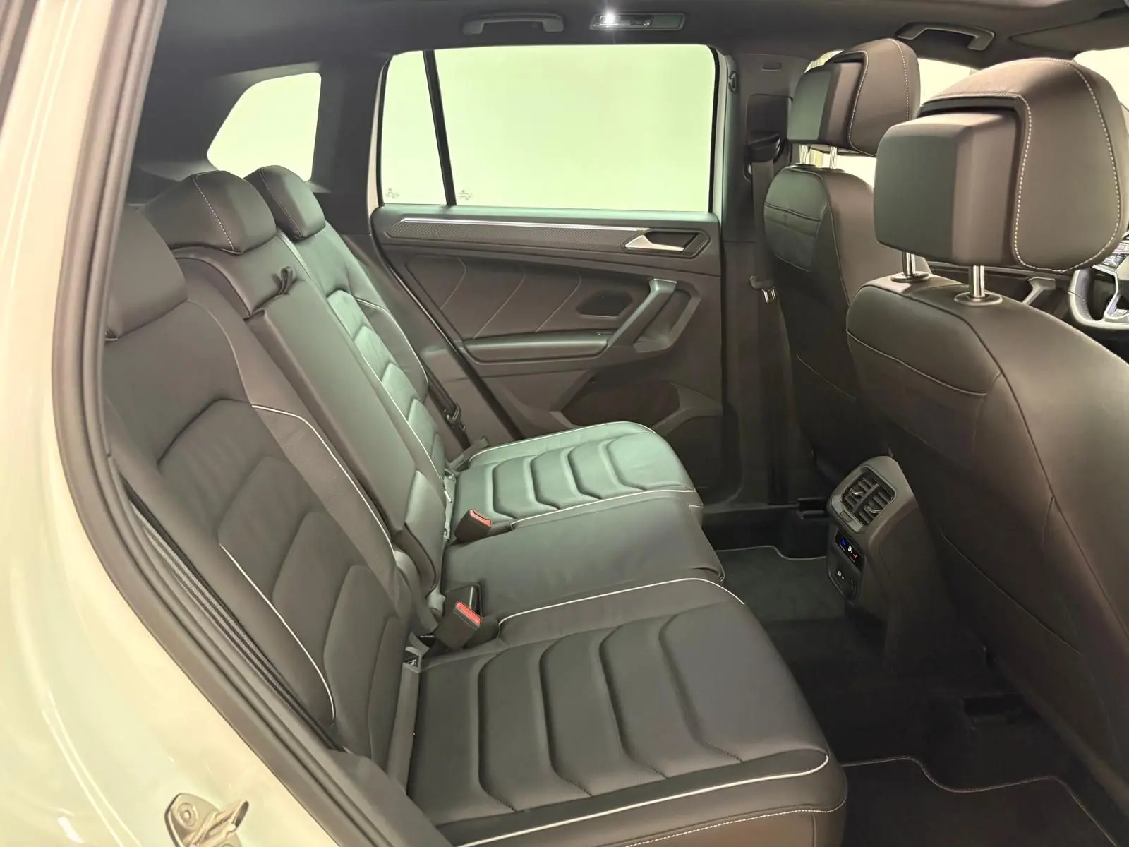 Vue intérieure côté gauche des sièges arrière en cuir noir avec surpiqûres blanches du Volkswagen Tiguan 1.4 eHybrid 2023 blanc pur R-Line Exclusive.
