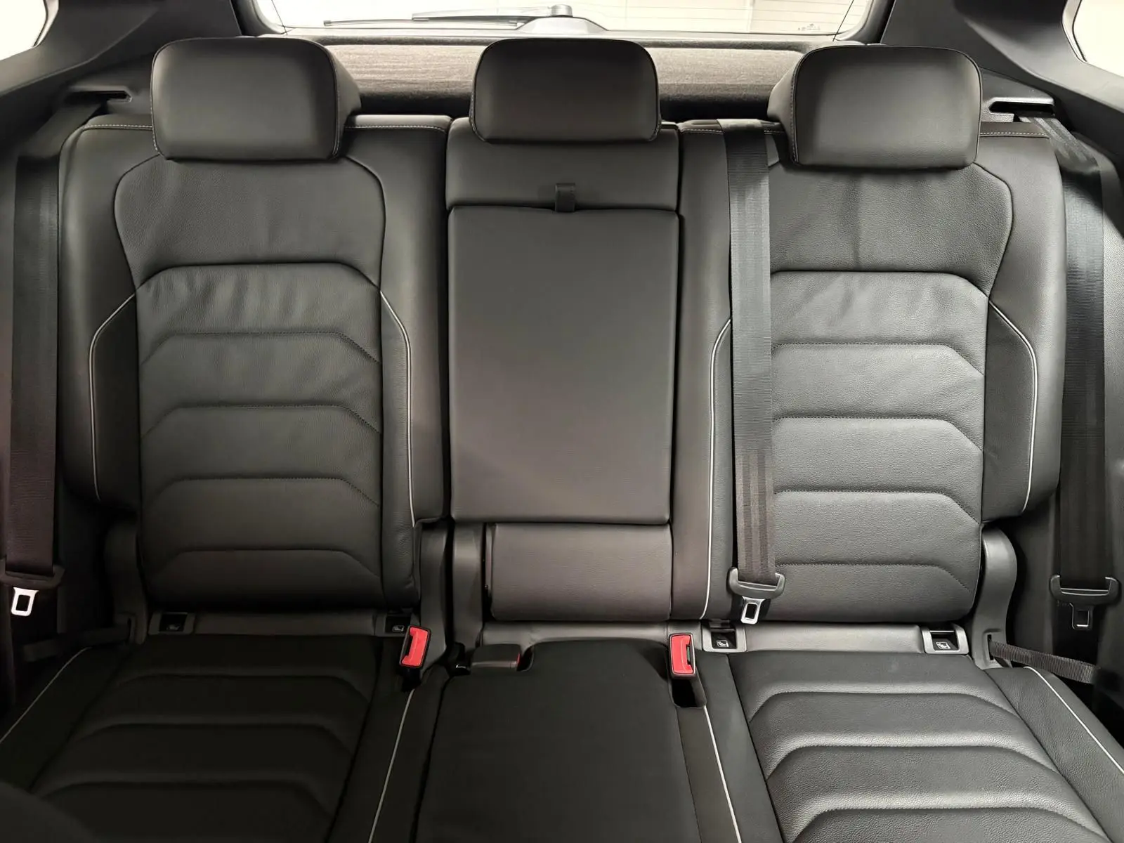 Vue intérieure des sièges arrière en cuir noir du Volkswagen Tiguan 1.4 eHybrid 2023, avec appuie-têtes et ceintures visibles.