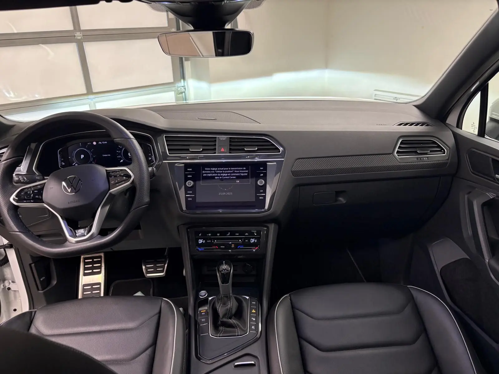 Vue intérieure du Volkswagen Tiguan 1.4 eHybrid 2023, tableau de bord et console centrale noirs avec finition R-Line exclusive.