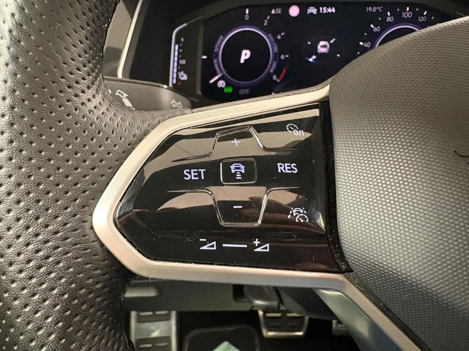 Gros plan sur les commandes de régulateur de vitesse au volant perforé du Volkswagen Tiguan blanc pur 2023 hybride rechargeable.