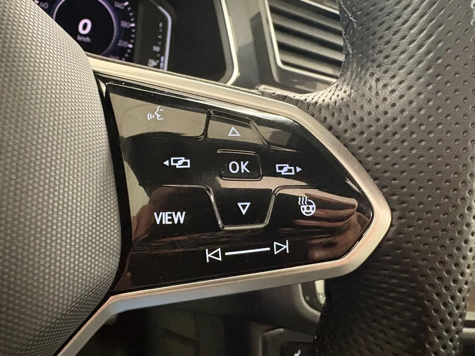 Gros plan sur les commandes multifonctions du volant en cuir perforé du Volkswagen Tiguan 1.4 eHybrid blanc pur 2023.